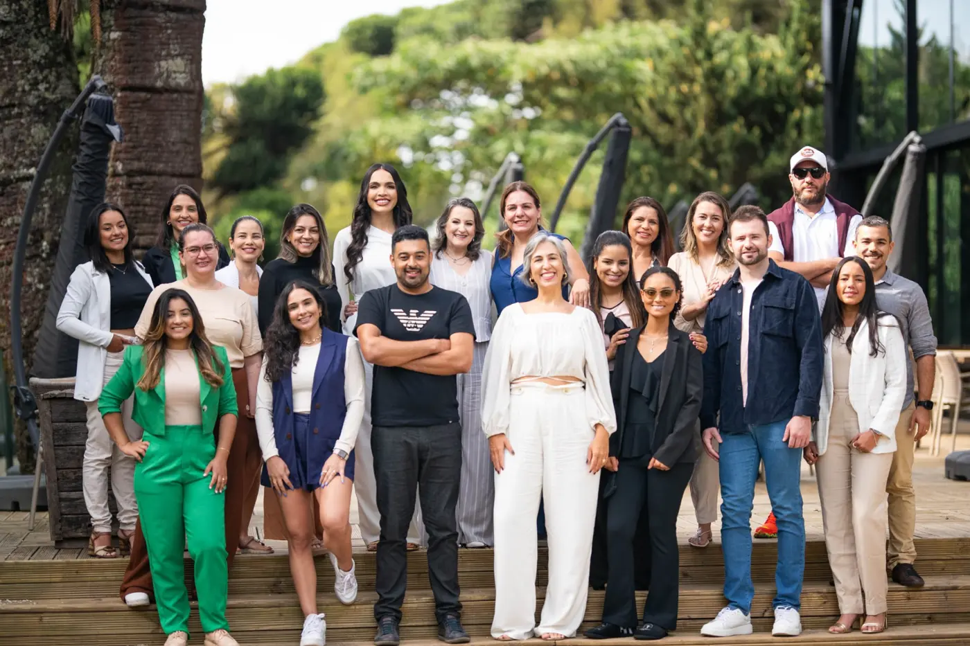 Grupo de mentoradas reunidas em degraus de madeira ao ar livre